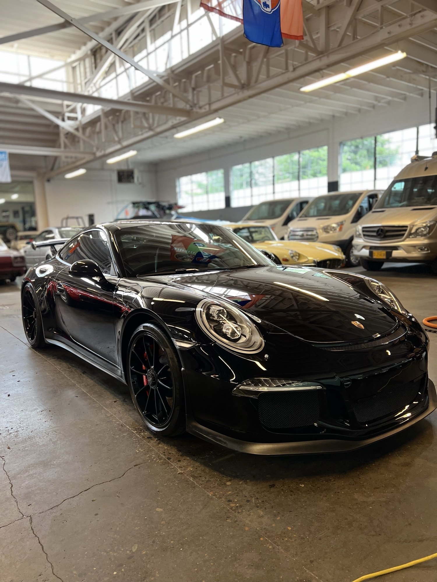 Black Porsche with reflections across its hood and bodywork
